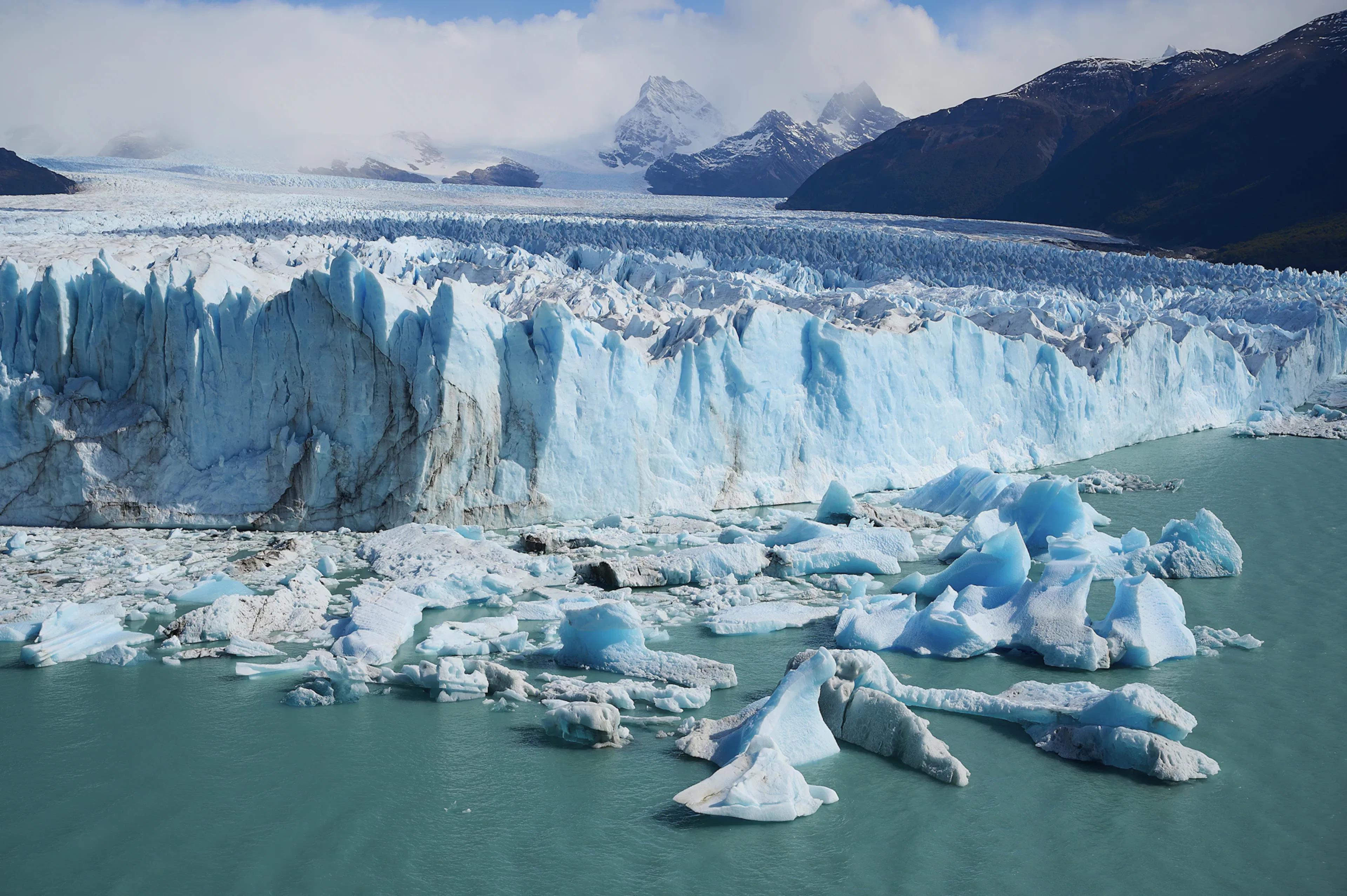 Massive glacier with turquoise water and floating icebergs