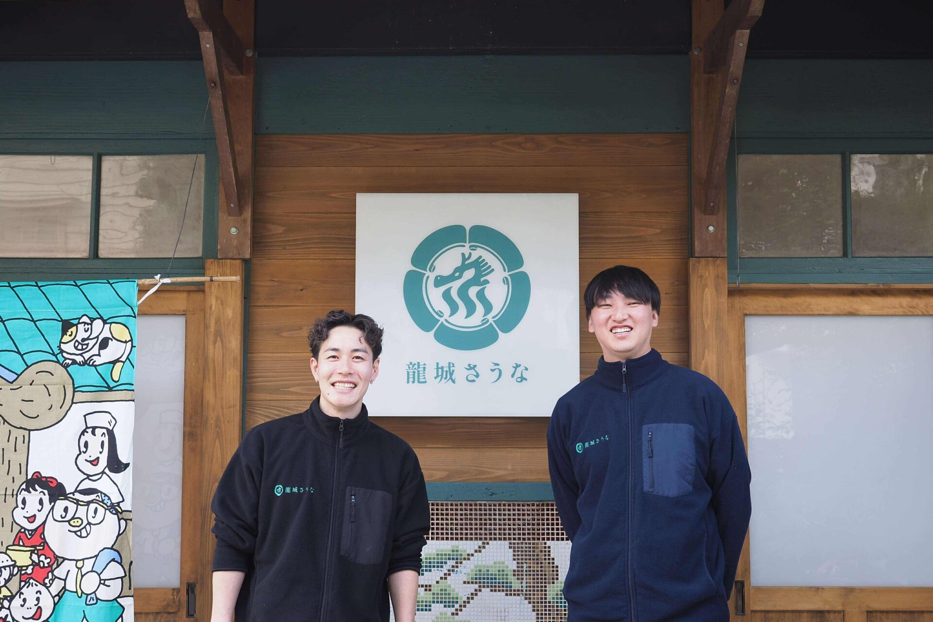 龍城さうな 入口の看板前に立つスタッフ